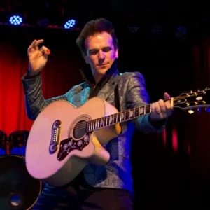 Photo of Tommy Memphis enthusiastically playing guitar