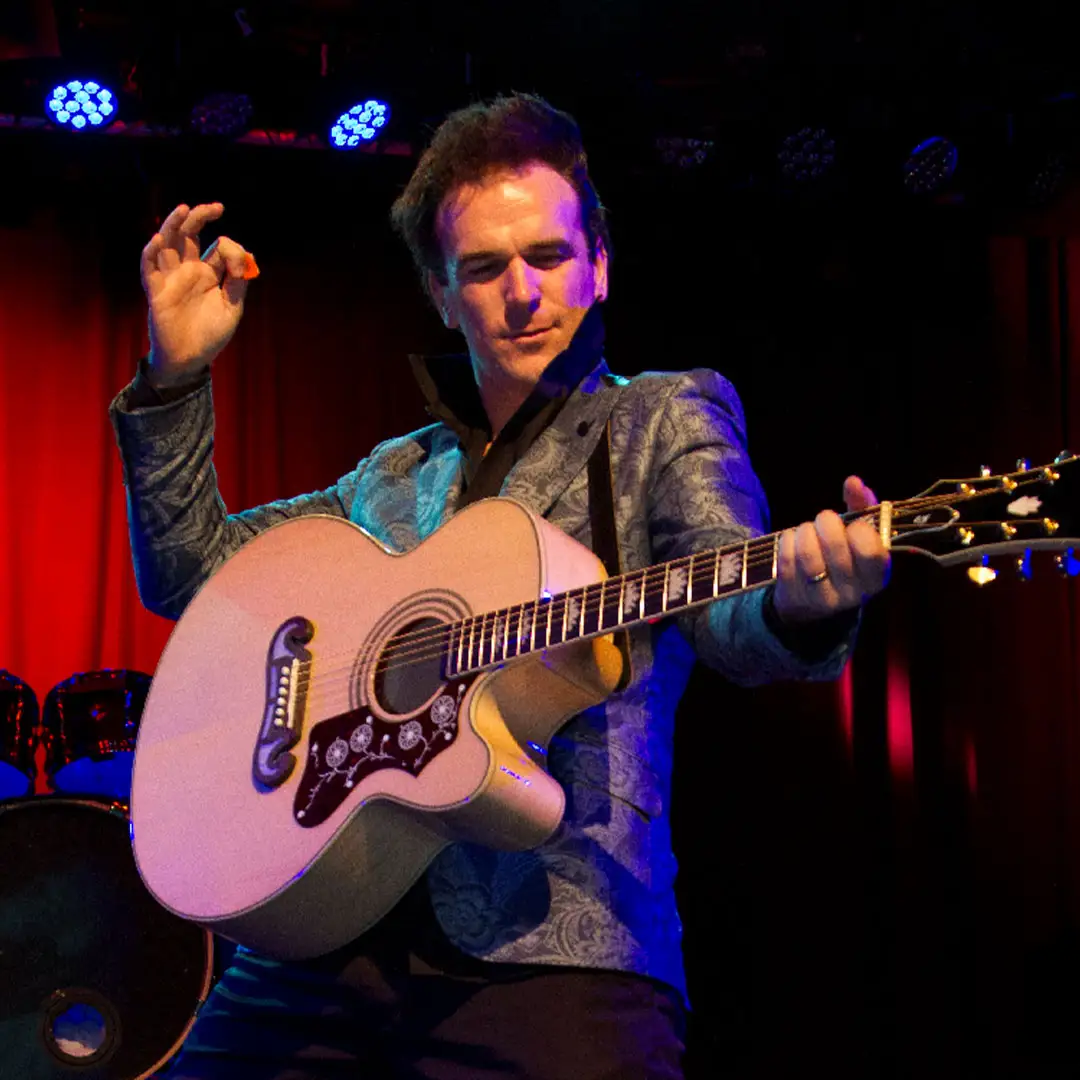 Photo of Tommy Memphis enthusiastically playing guitar